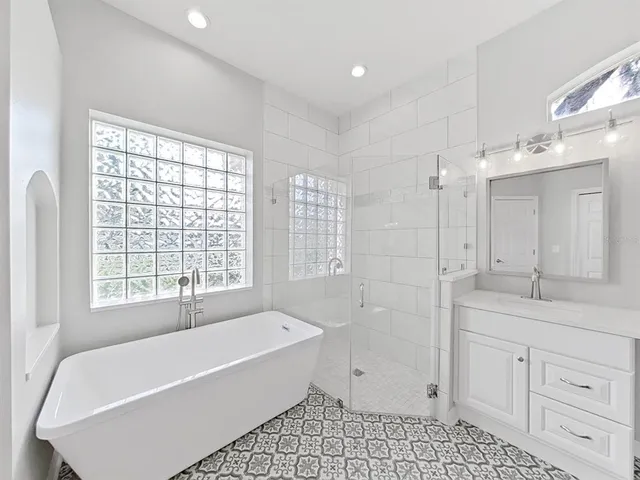 a bathroom with a bathtub a sink a vanity and a shower
