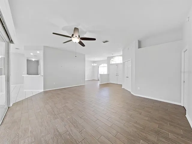 a view of empty room with wooden floor and ceiling fan