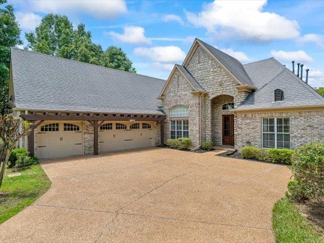 Stone and brick exterior with a large driveway