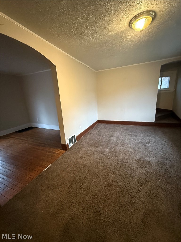 805 Carpenter Street Akron, OH 44310 - Photo 8 of 8 Spare room featuring arched walkways, a textured ceiling, and dark colored carpet