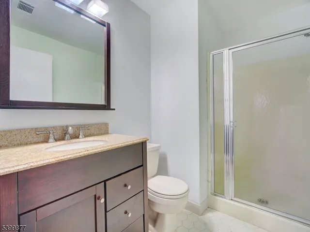 a bathroom with a granite countertop sink mirror vanity and toilet
