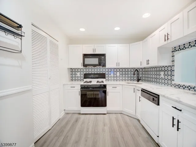 a kitchen with granite countertop white cabinets and stainless steel appliances