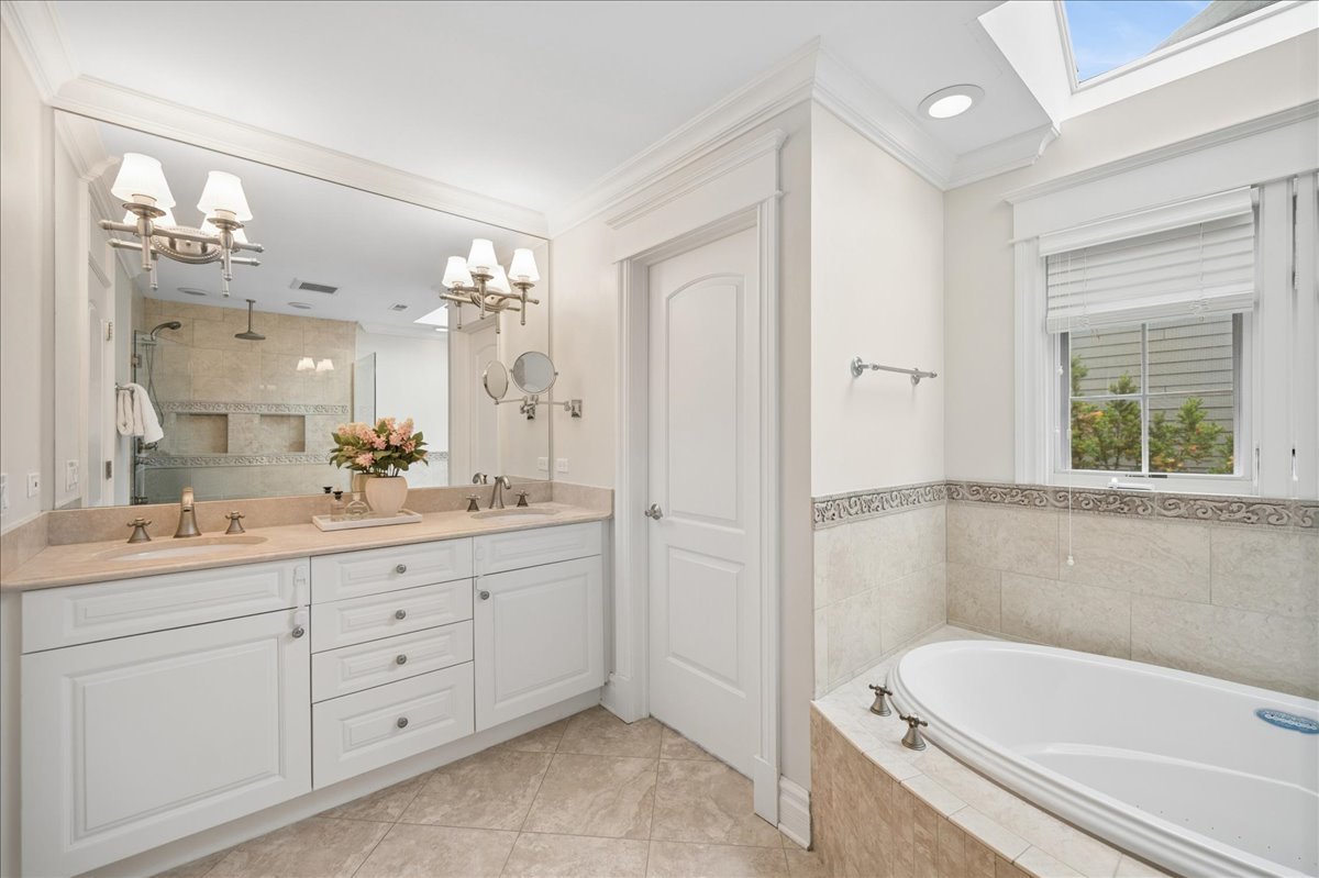 556 Willow Road Winnetka, IL 60093 - Photo 24 of 43 a bathroom with a tub a sink and a large mirror