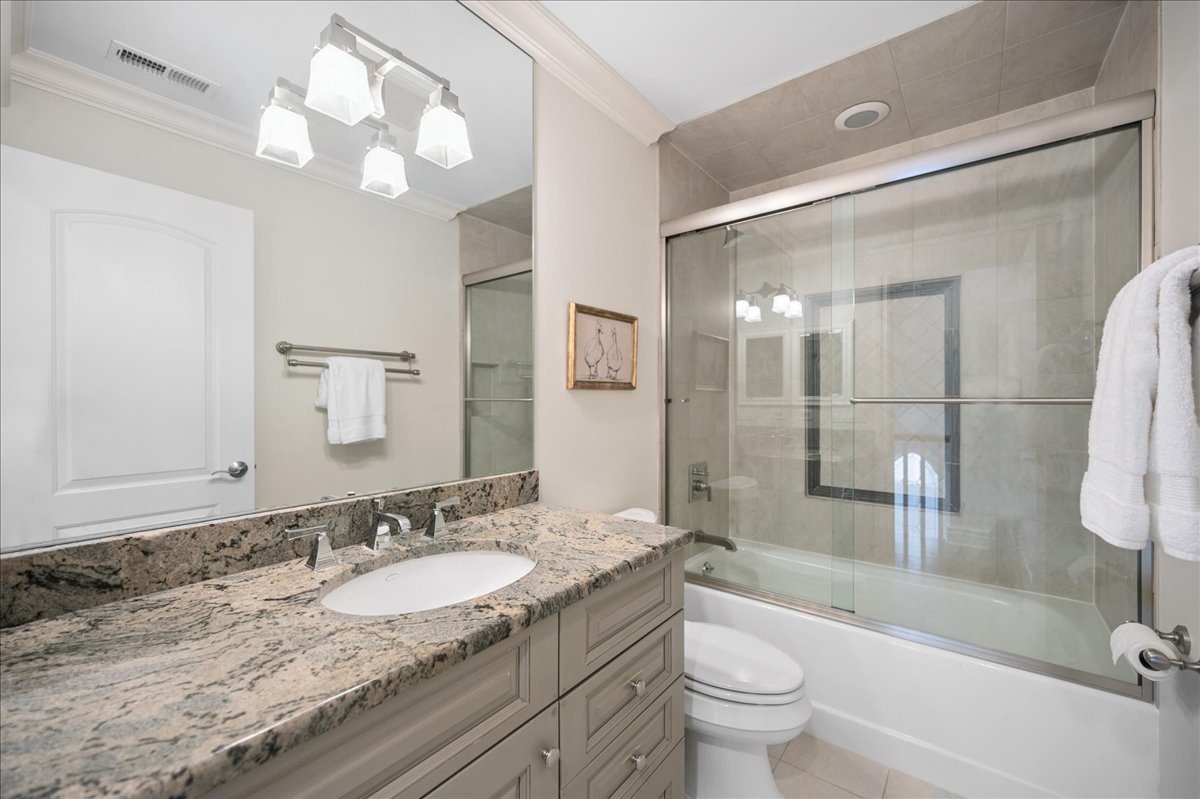 556 Willow Road Winnetka, IL 60093 - Photo 28 of 43 a bathroom with a granite countertop sink a toilet a mirror a vanity and shower