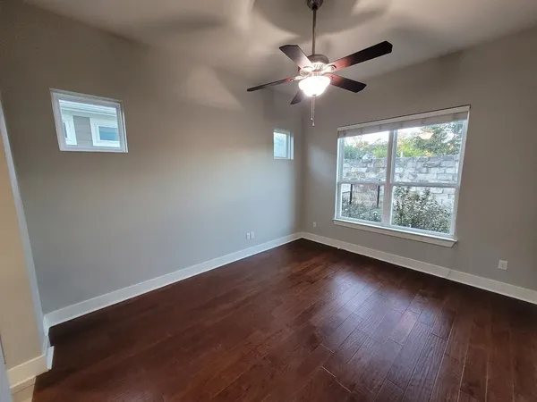 a view of an empty room with wooden floor and a window