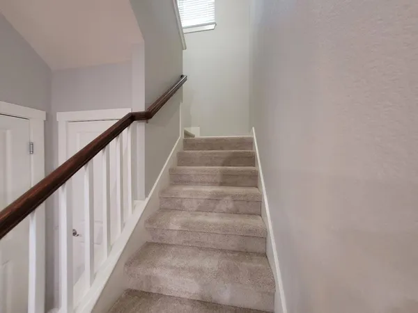 a view of staircase with lots of frames on wall and a window