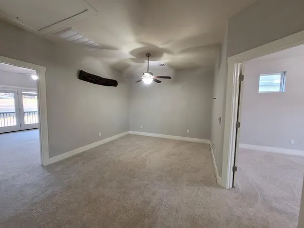 en empty room with windows and ceiling fan