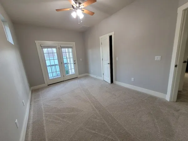 an empty room with windows and fan