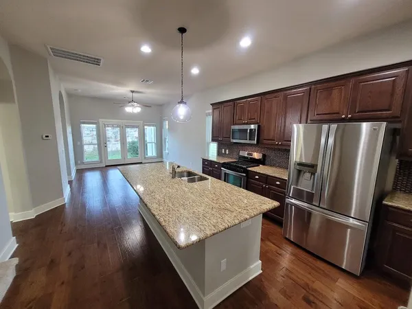 a kitchen with stainless steel appliances wooden floor and wooden cabinets