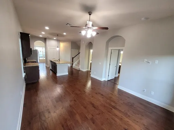 an empty room with wooden floor a refrigerator and a chandelier