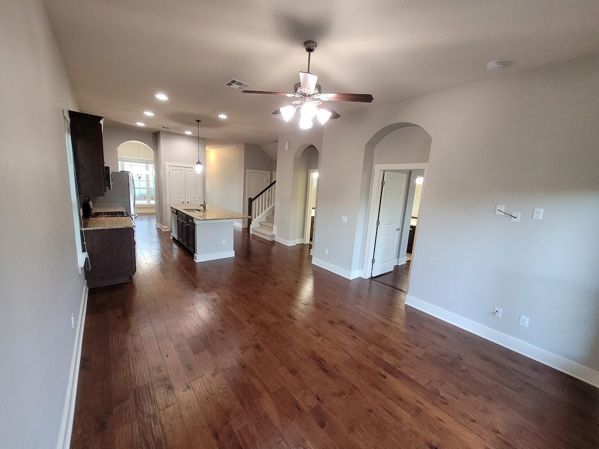 2404 Vintage Stave Road, Unit 102 Austin, TX 78748 - Photo 10 of 39 an empty room with wooden floor a refrigerator and a chandelier