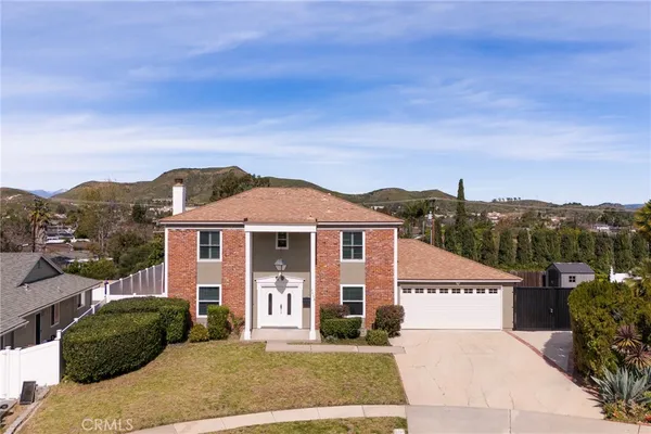 a front view of a house with a yard and mountain view