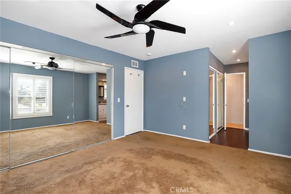 a view of a big room with windows and ceiling fan