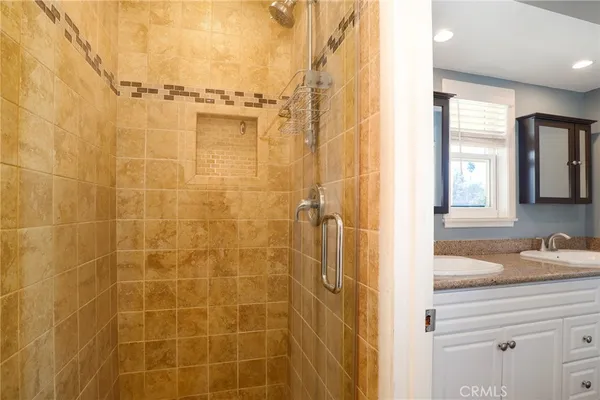 a bathroom with a granite countertop shower a sink and a mirror