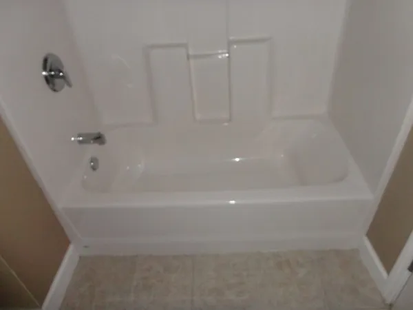 an empty room with a chandelier fan and wooden floor