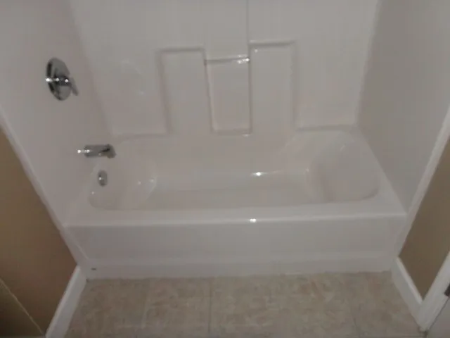 an empty room with a chandelier fan and wooden floor