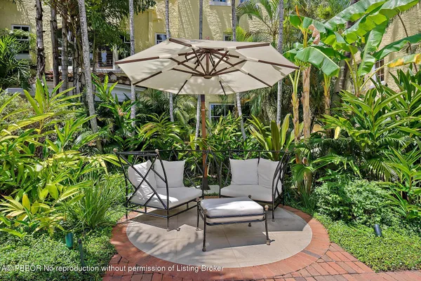 a backyard of a house with table and chairs under an umbrella