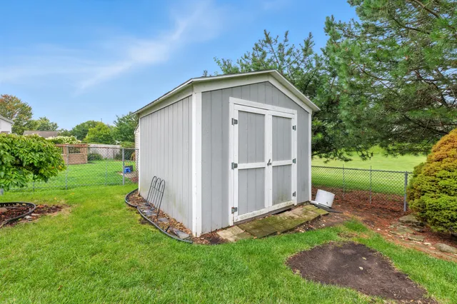a view of a white house in front of a big yard with large trees