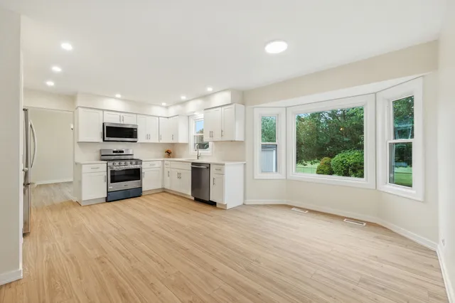 a kitchen with wooden floors a sink stainless steel appliances and cabinets