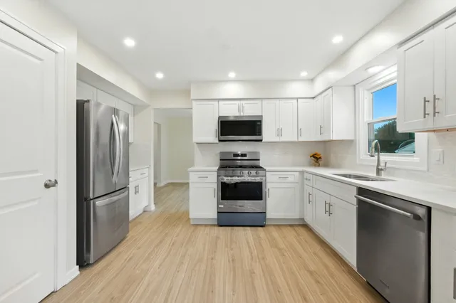 a kitchen with cabinets stainless steel appliances and wooden floor