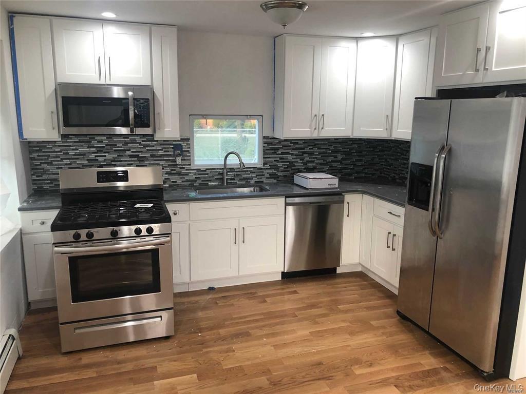 127-22 Hawtree Creek Road Queens, NY 11420 - Photo 4 of 12 a kitchen with stainless steel appliances a stove a sink a microwave a refrigerator and cabinets