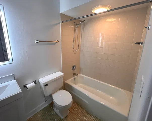a bathroom with a granite countertop bathtub shower sink vanity and toilet