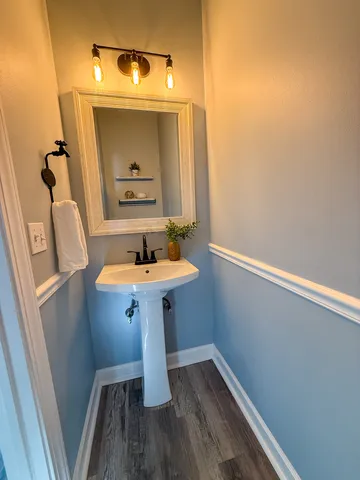 a bathroom with a sink a mirror and wooden floor