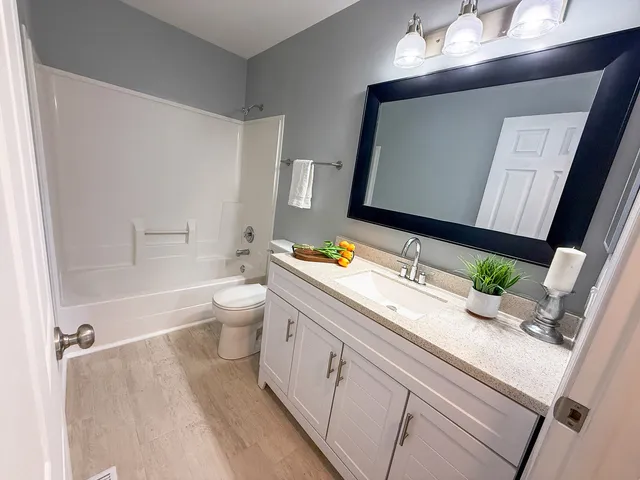 a bathroom with a granite countertop bathtub sink vanity mirror and toilet