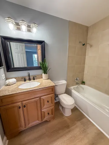 a bathroom with a granite countertop sink toilet mirror and bathtub