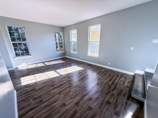 a view of an empty room with window and wooden floor