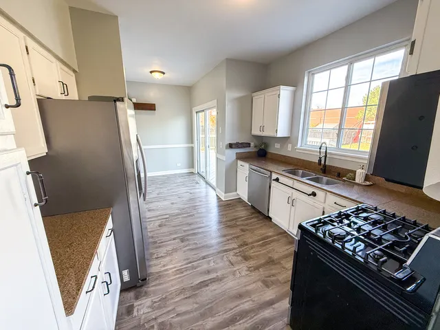 a kitchen with stainless steel appliances a refrigerator a stove a sink and a window