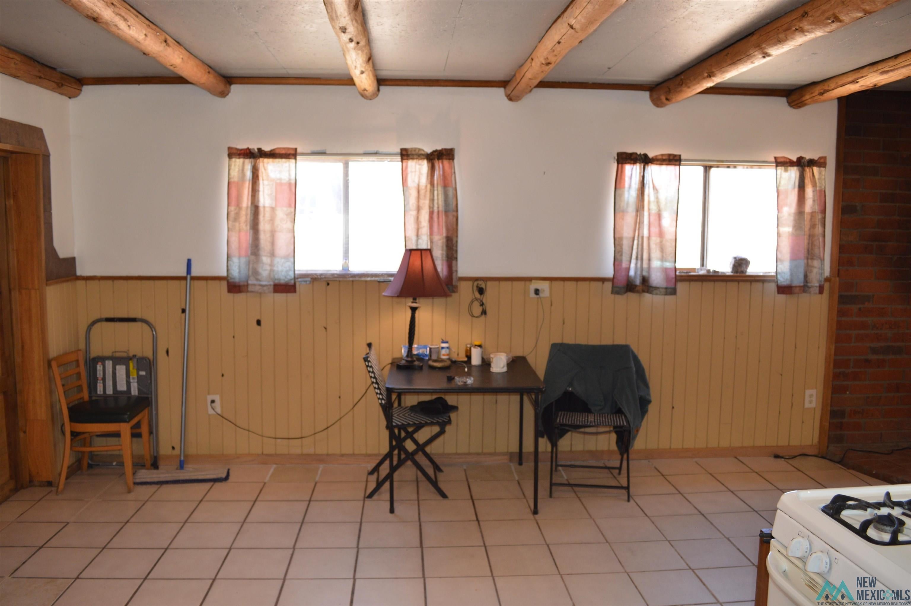 6 Sunny Dale Road Bluewater, NM 87005 - Photo 32 of 42 Rustic interior featuring exposed wood ceiling beams, two windows, wainscoting, and tile flooring