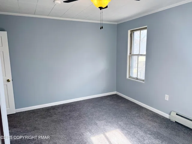 an empty room with windows and chandelier fan