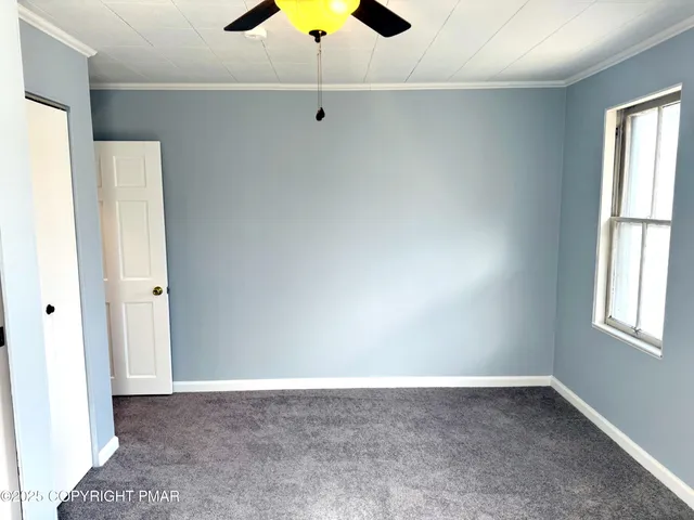 an empty room with a window and a ceiling fan