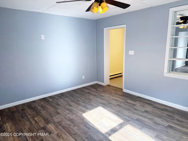 a view of an empty room with window and wooden floor