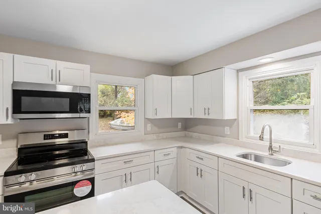 a kitchen with cabinets appliances a sink and a window