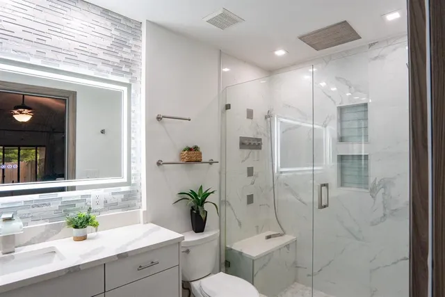 a bathroom with a shower sink vanity mirror and toilet