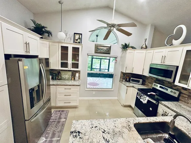 a kitchen with stainless steel appliances kitchen island granite countertop a refrigerator stove and sink
