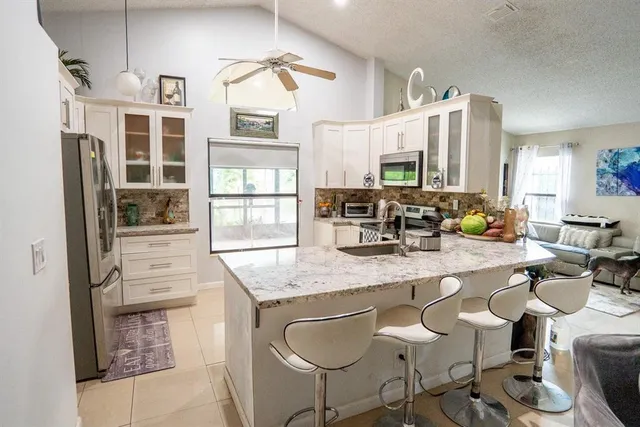 a kitchen with a dining table chairs cabinets and stainless steel appliances
