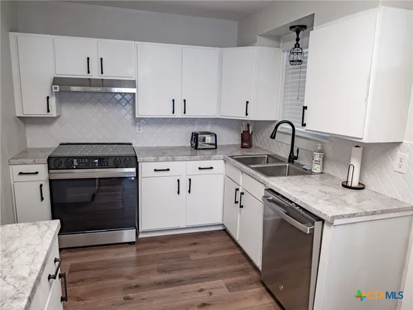 a kitchen with granite countertop a refrigerator and a stove top oven