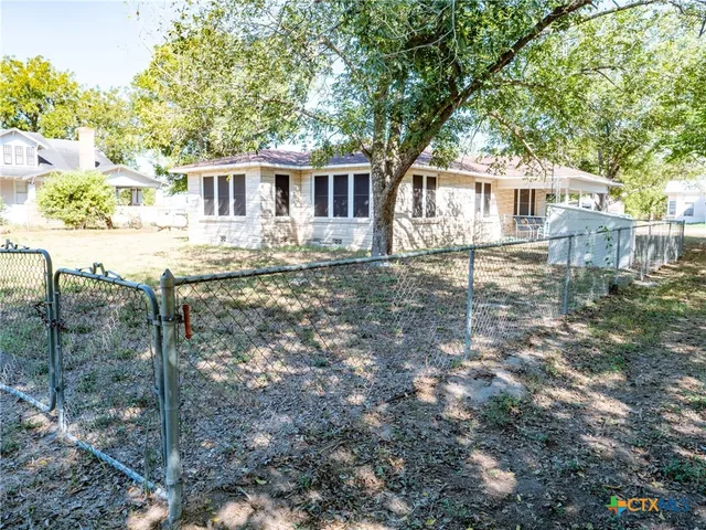 a view of a yard in front of a house with large tree