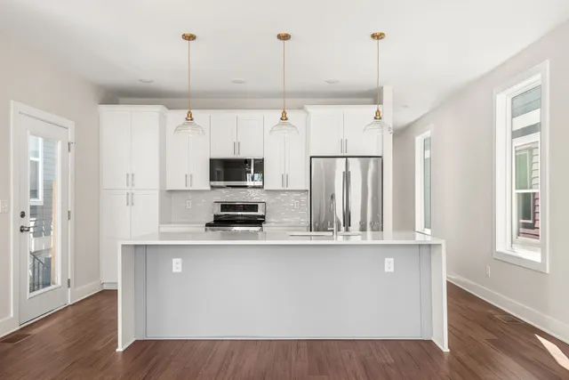 a kitchen with stainless steel appliances granite countertop a refrigerator a stove a sink and a wooden floors