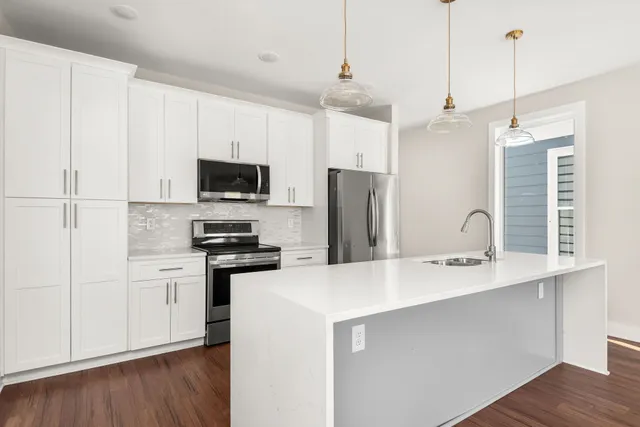 a kitchen with stainless steel appliances a refrigerator a sink a stove a microwave and wooden floors