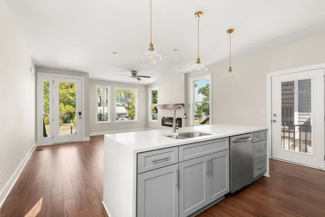 a view of a kitchen and a sink wooden floor windows and a living room