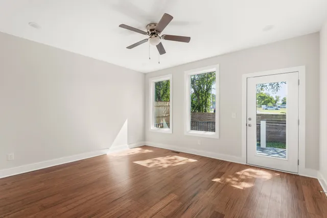 a view of empty room with wooden floor and fan