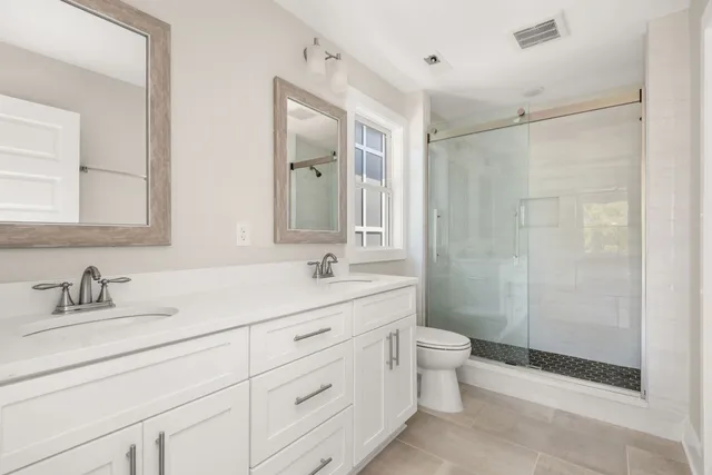a bathroom with a double vanity sink toilet mirror and shower