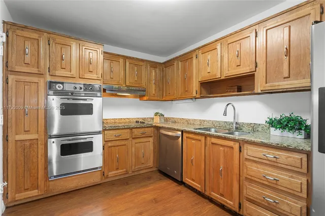 a kitchen with granite countertop stainless steel appliances a refrigerator and cabinets