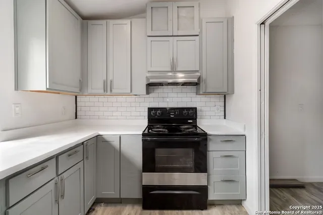 a kitchen with stainless steel appliances granite countertop white cabinets and a stove top oven
