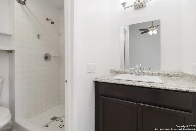 a bathroom with a granite countertop sink a toilet and shower