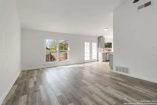 an empty room with wooden floor and windows